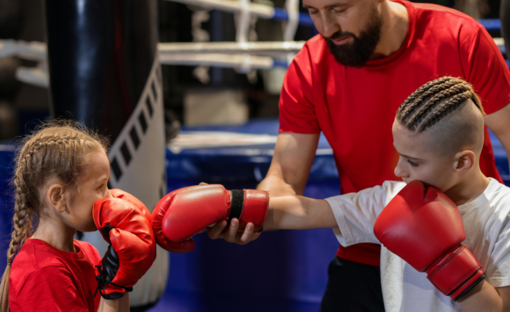 Profesor de artes marciales enseñando técnicas a dos alumnos durante una clase en una escuela de artes marciales.